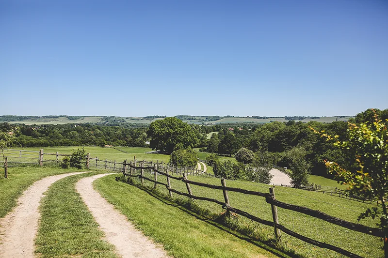A track and fence looking across the valley at Greenhill Farm toward the North Downs